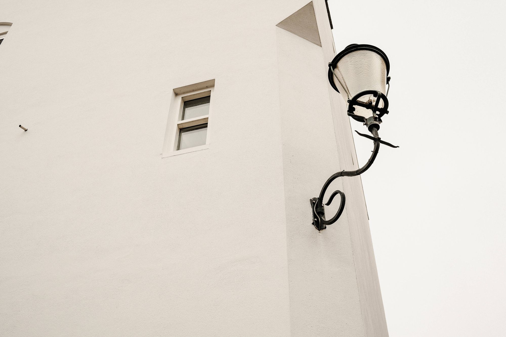 a minimal-looking image of a white building with a lamppost