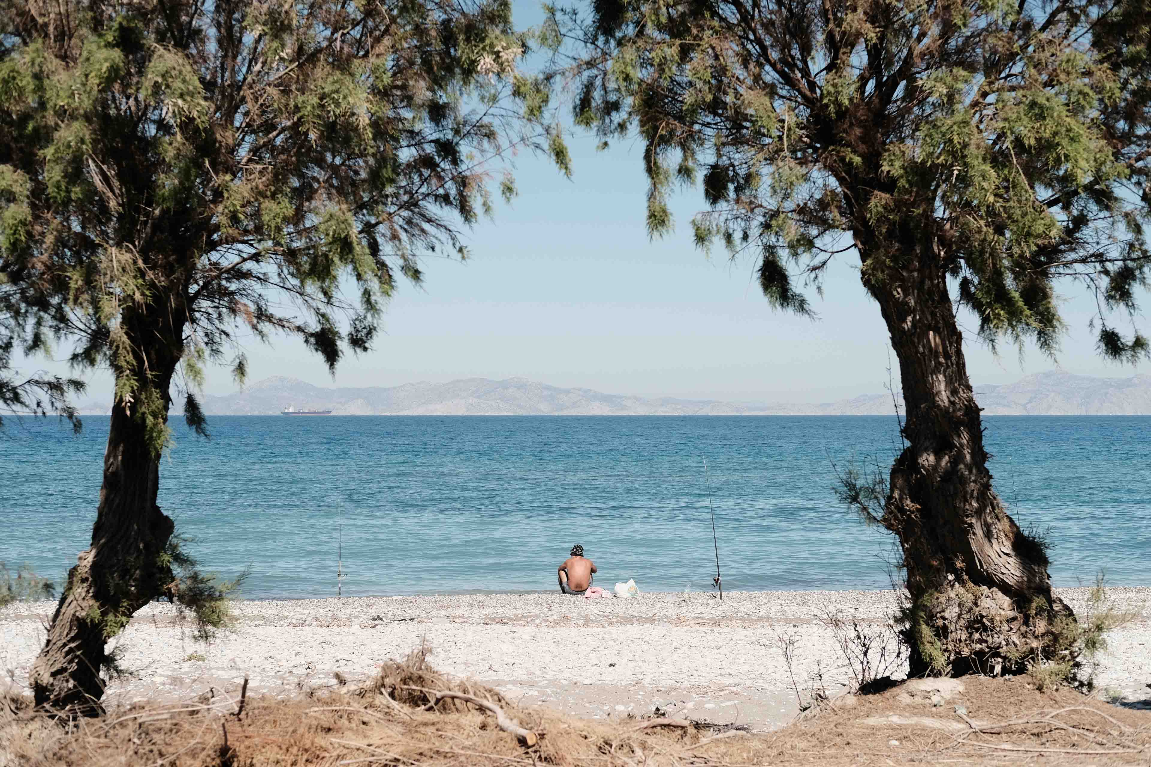 a fisherman sitting by the ocean, waiting for fish to catch on