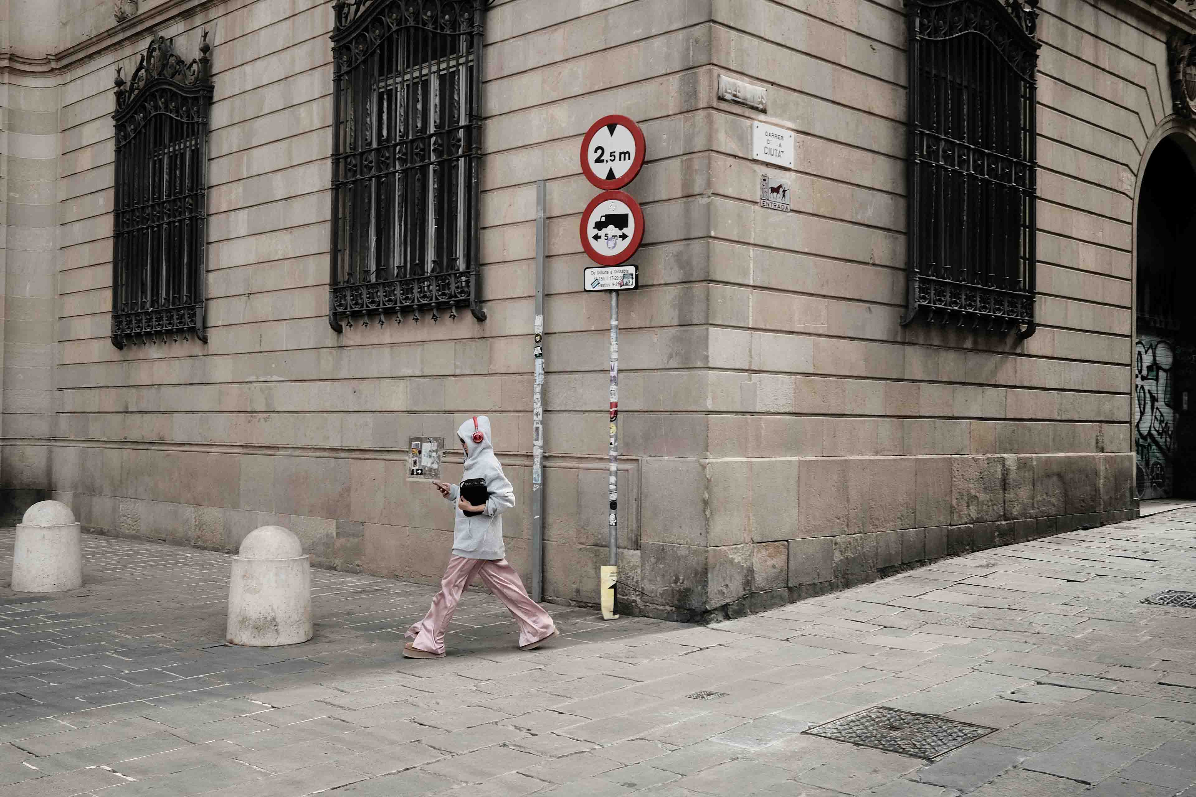 A lady walking swiftly through the streets of the gothic quarter in Barcelona