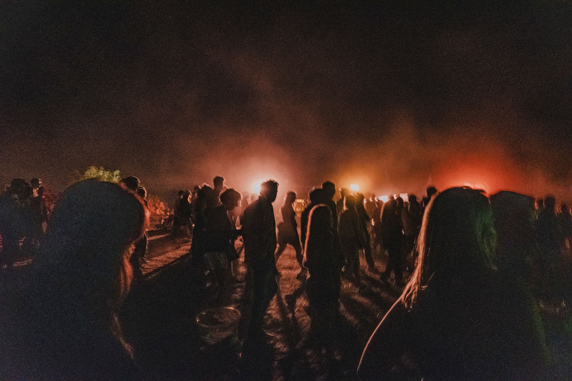 A group of people backlit by a red light with a lot of dust and smoke in the air.