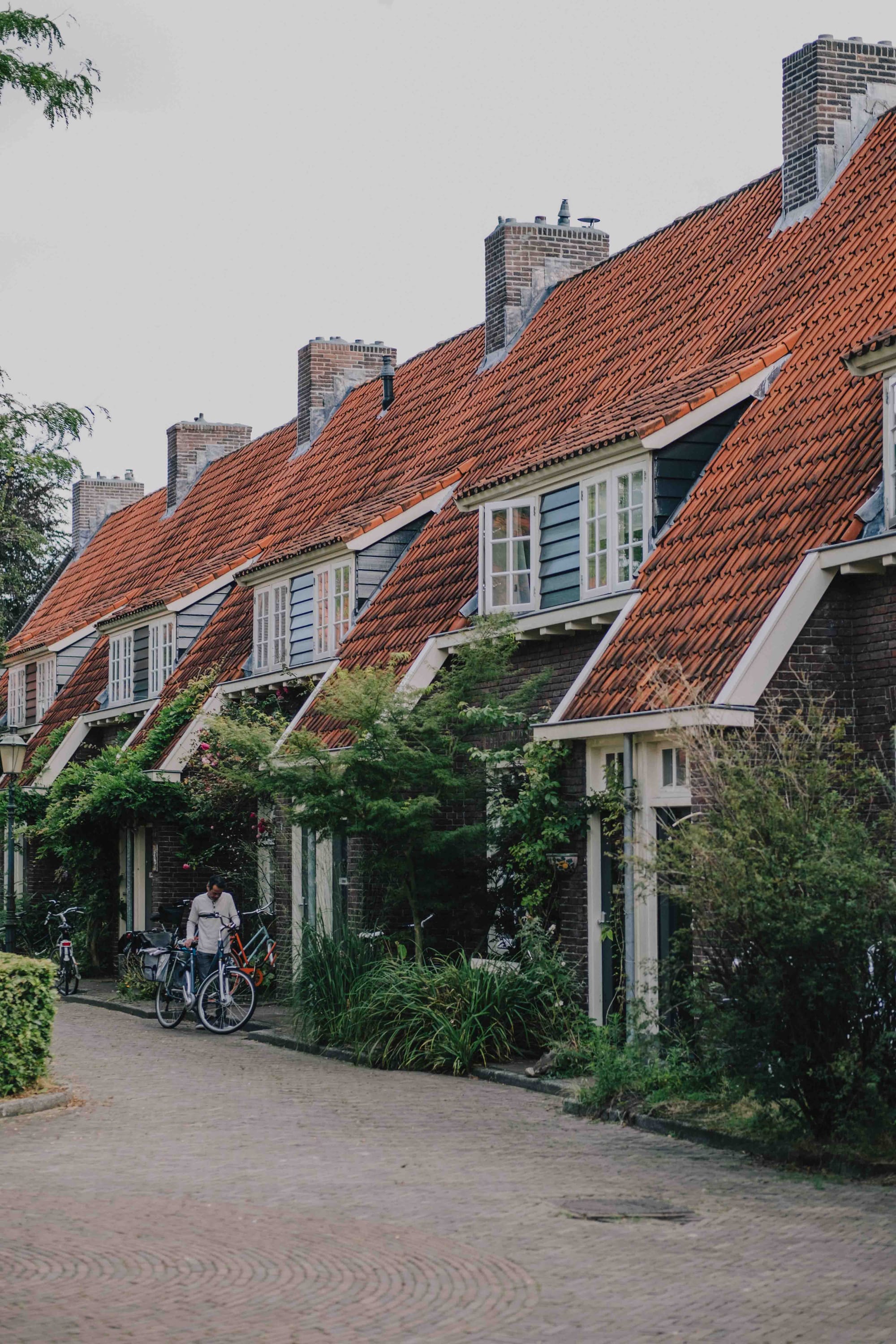 A guy standing with his bicycle in front of a row of old houses, downtown Amersfoort.